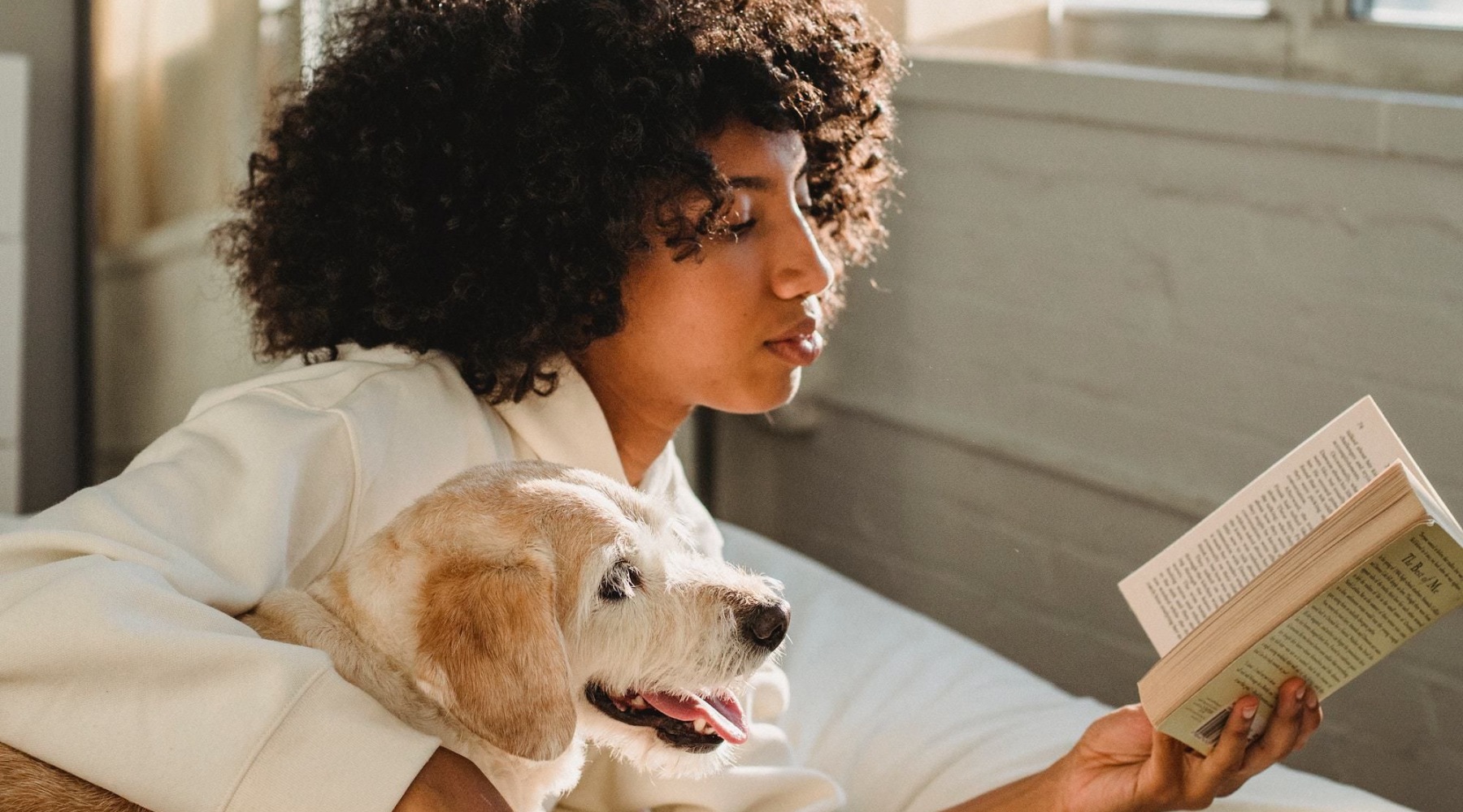 a person reading a book with a dog by them